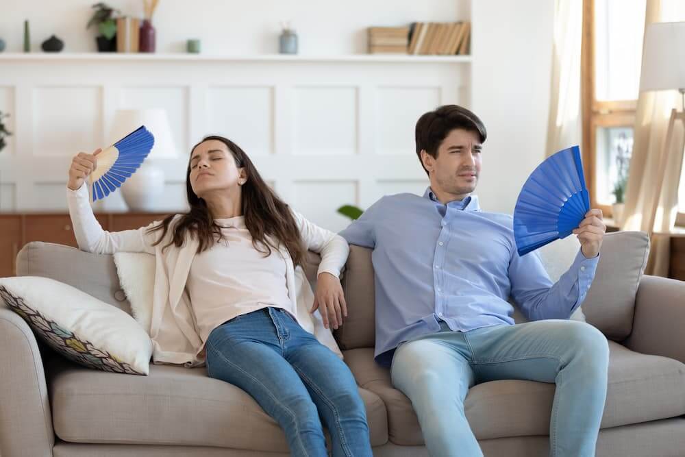 man and women fanning themselves on the couch because its hot